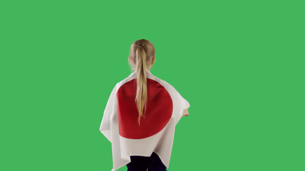 una bandera japonesa en la parte de atrás de un niño en la pantalla verde de chroma key.