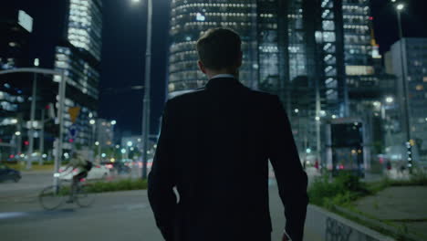 elegant young male in suit strolling at night in modern illuminated city