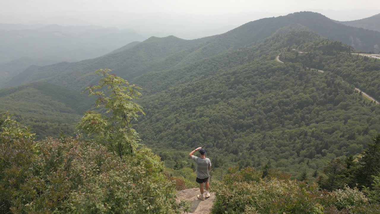 joven disfruta de la vista del valle del bosque desde el punto de vista de las montañas humeantes