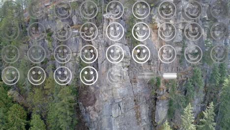 composición digital de filas de múltiples emojis de caras sonrientes contra una vista aérea de una montaña