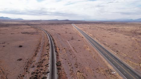 Drohnenaufnahme-Einer-Modernen-Autobahn-Und-Alter-Eisenbahnschienen,-Die-In-Die-Ferne-Führen