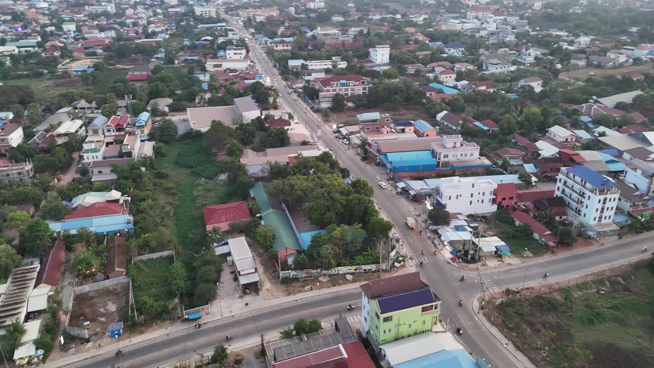 Aerial view of Krong Siem Reap, Cambodia, showing a green urban landscape with a main road, traffic, and diverse low-rise buildings. Ideal for showcasing a bustling Southeast Asian city.