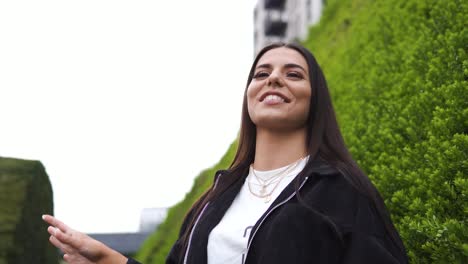 brunette positive female in nature laughing genuine smiling fashionable wearing jewellery gold silver blurry backround good times slow motion