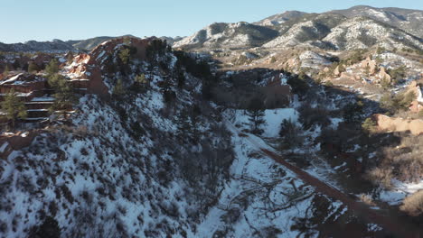 aerial dolly forward next to red rock ridge covered in snow