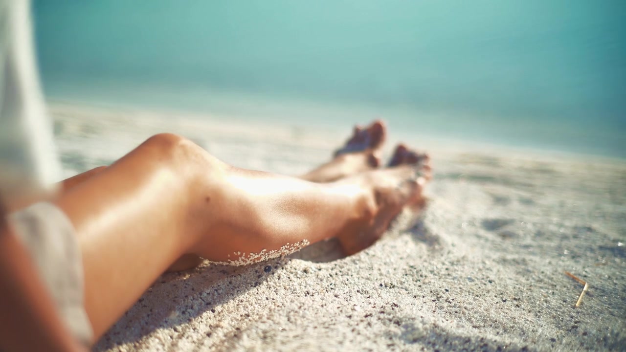 Donna che si rilassa e gioca con la sabbia su una spiaggia soleggiata