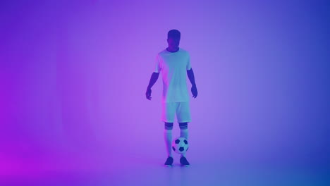 hombre negro un jugador hace malabares con una pelota de fútbol en un estudio oscuro con luces de neón en el suelo y efectos de iluminación roja y azul en cámara lenta. jugador de fútbol profesional africano