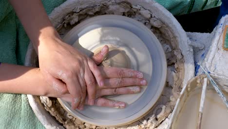 top view on potter's hands work with clay on a potter's wheel