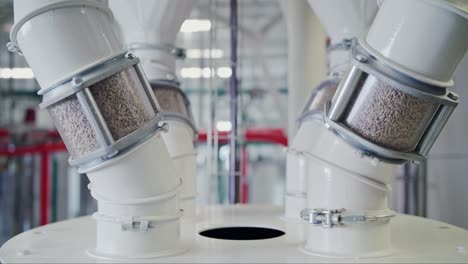 dolly shot of grain pouring through inspection tubes at a state-of-the-art grain mill facility, showcasing large-scale food production on an industrial level