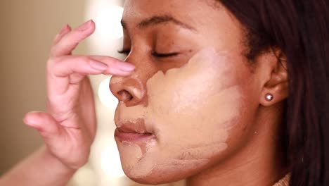 a female makeup artist applying gold makeup to a black african-american model. the concept of beauty and makeup