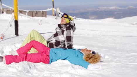 Couple-resting-on-hill-after-skiing