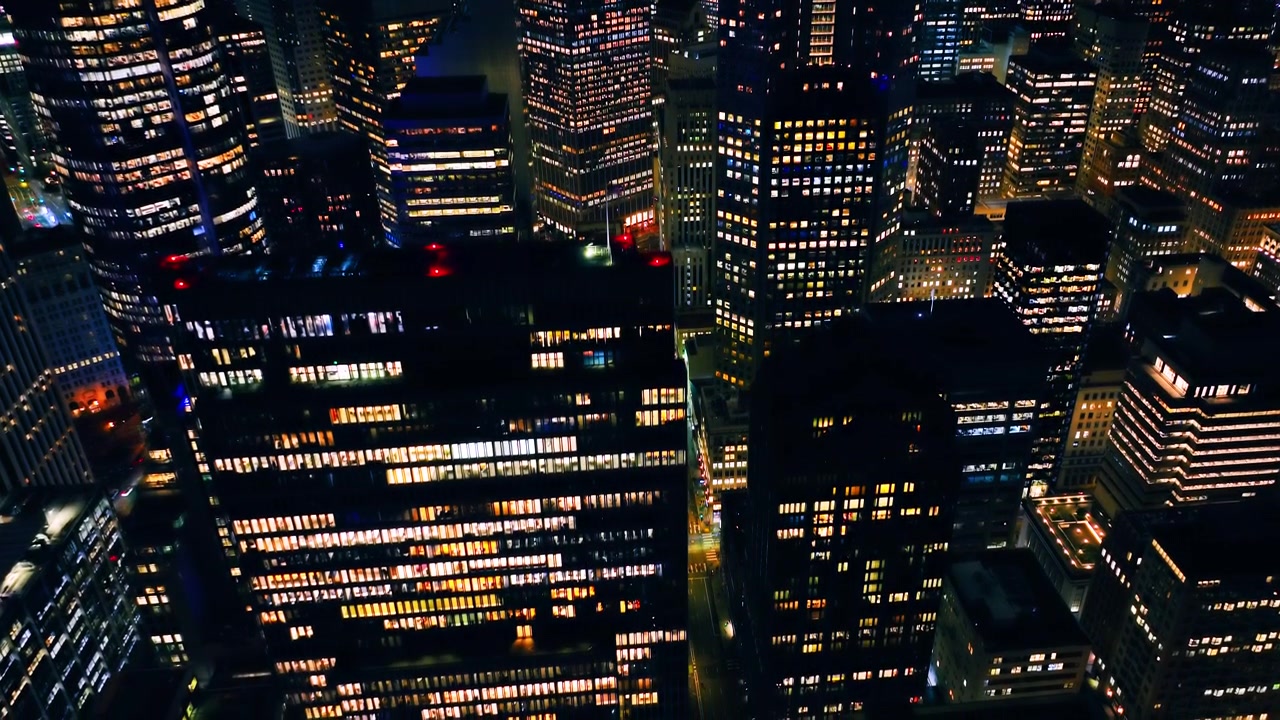 Torri per uffici illuminate di notte, San Francisco. Vista aerea di un corridoio stradale notturno, griglie di finestre ambra calde e blu fredde, luci faro rosse sui tetti