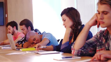 bored colleagues attending meeting in conference room