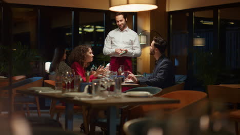 una pareja romántica pide a un camarero en un restaurante caro una mesa para cenar por la noche.