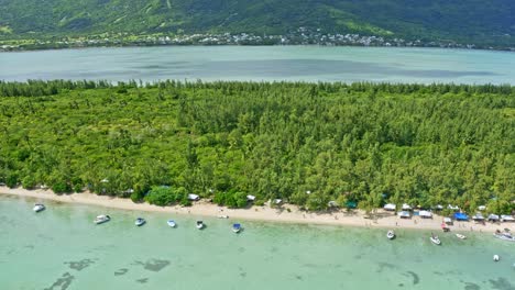 aerial view of ile aux benitiers beach by mauritius island, la gaulette town and green tropical lush, revealing drone shot