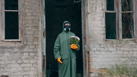 person at post-apocalyptic place. man in protective suit with flowers in abandoned place after ecological disaster. emission of radiation.