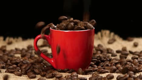 granos de café vertiendo en una taza roja