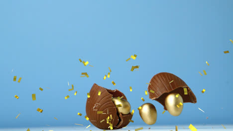 Animación-De-Confeti-Dorado-Sobre-Huevos-De-Pascua-De-Chocolate-Rompiéndose,-Con-Huevos-Dorados-En-Su-Interior,-En-Azul.