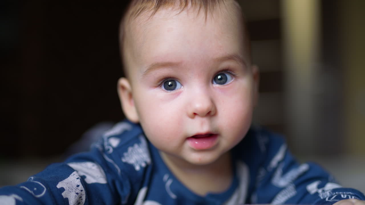 Adorable smile from a beautiful Caucasian kid lying on his belly. Close up. Blurred background.