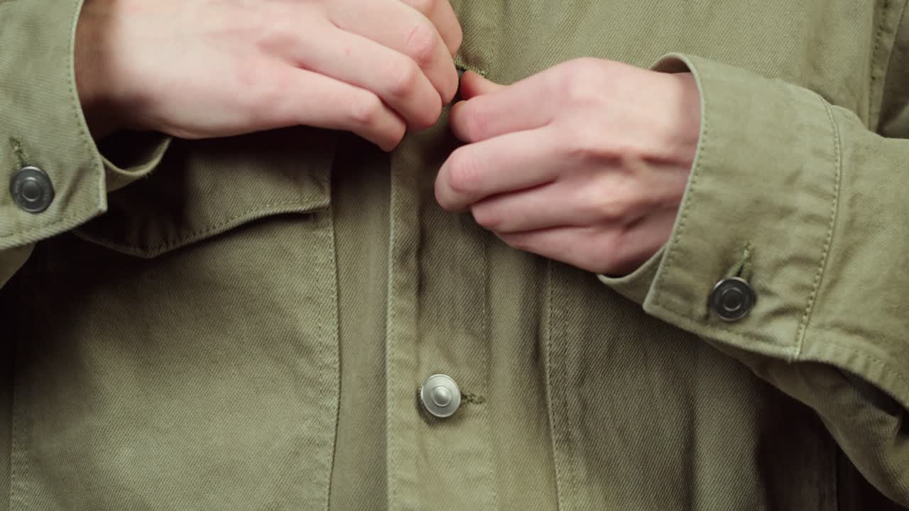 Primo piano di mani che abbottonano una giacca verde
