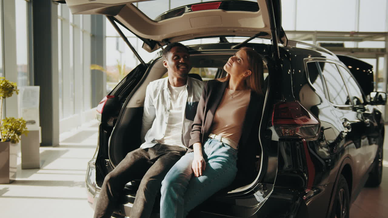 pareja explorando un nuevo maletero de coche en la sala de exposiciones