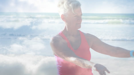 animation of glowing light over happy senior woman practicing yoga by seaside
