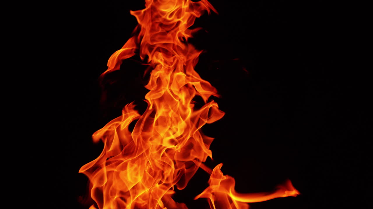 Hot fire flames twirling in the air. Long bonfire burning in the total darkness. Close up.