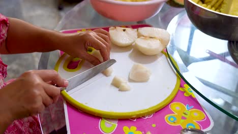 hands of woman cut fresh pear into small pieces, close up view