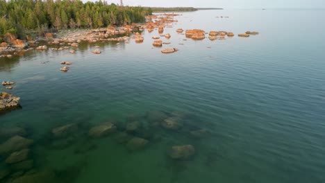 panorámica aérea sobre el agua a la costa con rocas, lago huron, michigan