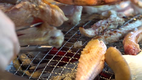 chicken on grill of korean barbecue with hot charcoal being turned around