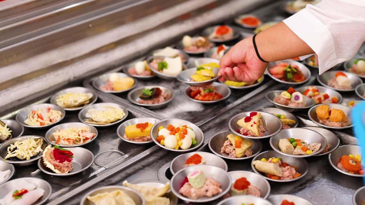 A chef arranges colorful dim sum in a bustling Phuket market. Bright lighting highlights the intricate details and vibrant ingredients