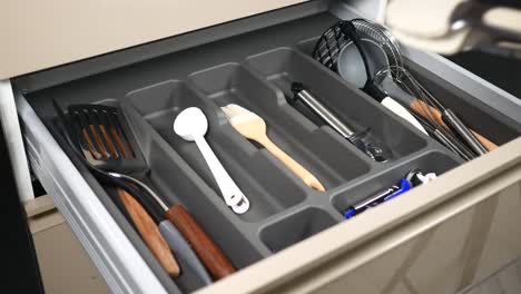 person organizing kitchen utensils in drawer