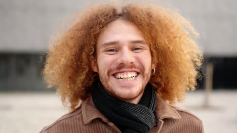 alternative young man with curly hair smiling at camera