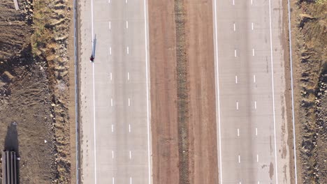 motocicletas que conducen por una nueva autopista de tres carriles con excavación de tuberías a los lados de las carreteras