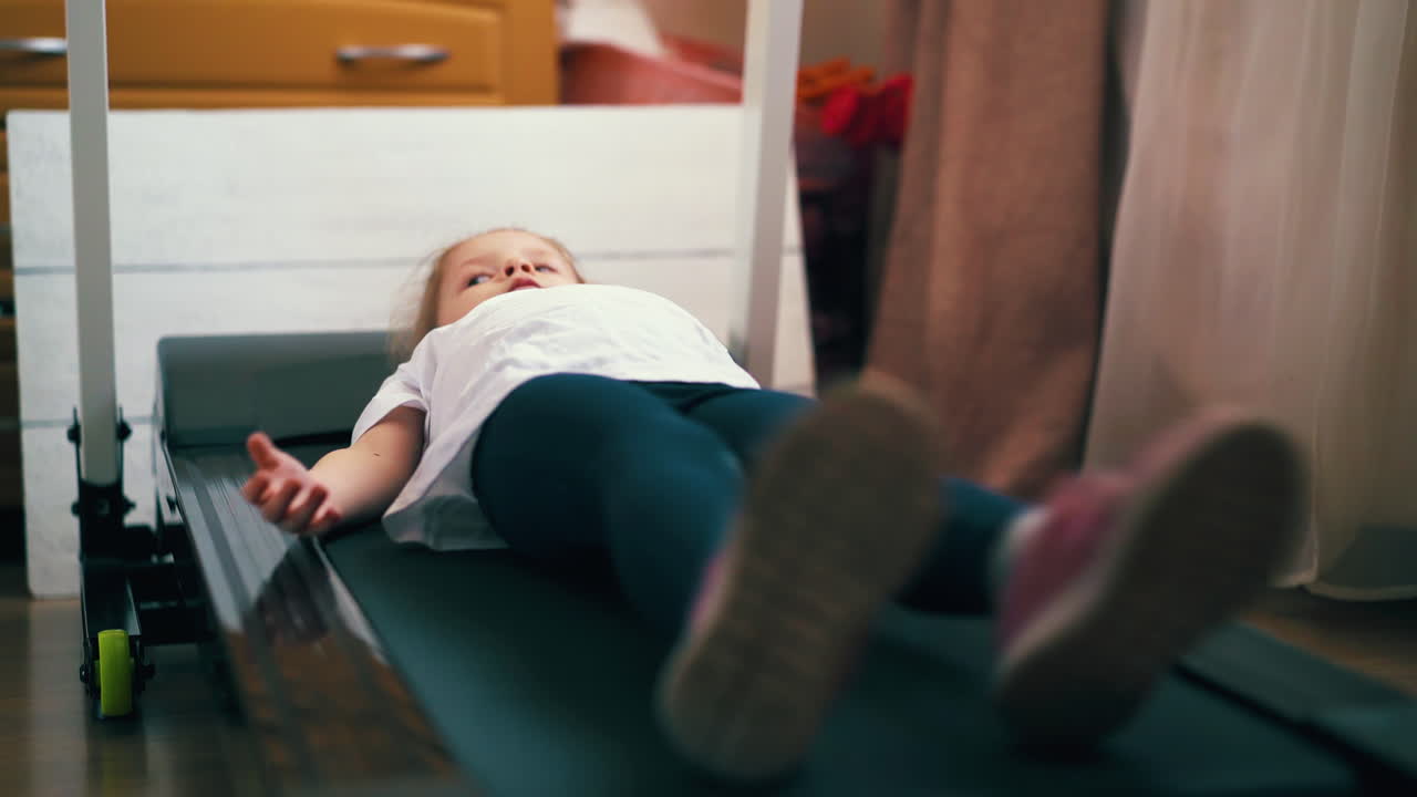 스포츠 의류 를 입은 행복 한 소녀 는 가 ⁇ 운 방 에 있는 트레드밀 에 누워 있다