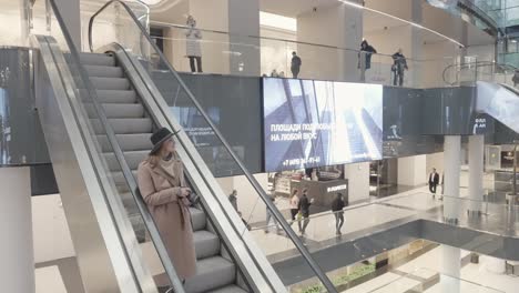 woman taking pictures on an escalator in a modern shopping mall.