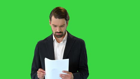 joven hombre de negocios mirando a través de los documentos en una pantalla verde, llave croma