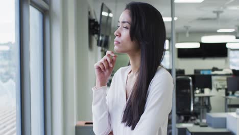 Thoughtful-woman-rubbing-her-chin-and-smiling-in-office