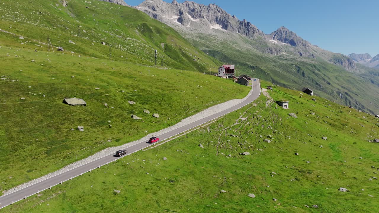 Bright summer day in Switzerland with road weaving through green slopes