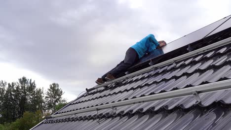 trabajador instalando paneles solares en el techo de una casa privada en noruega - trabajando encima del techo y usando herramientas para asegurar los paneles - noruega