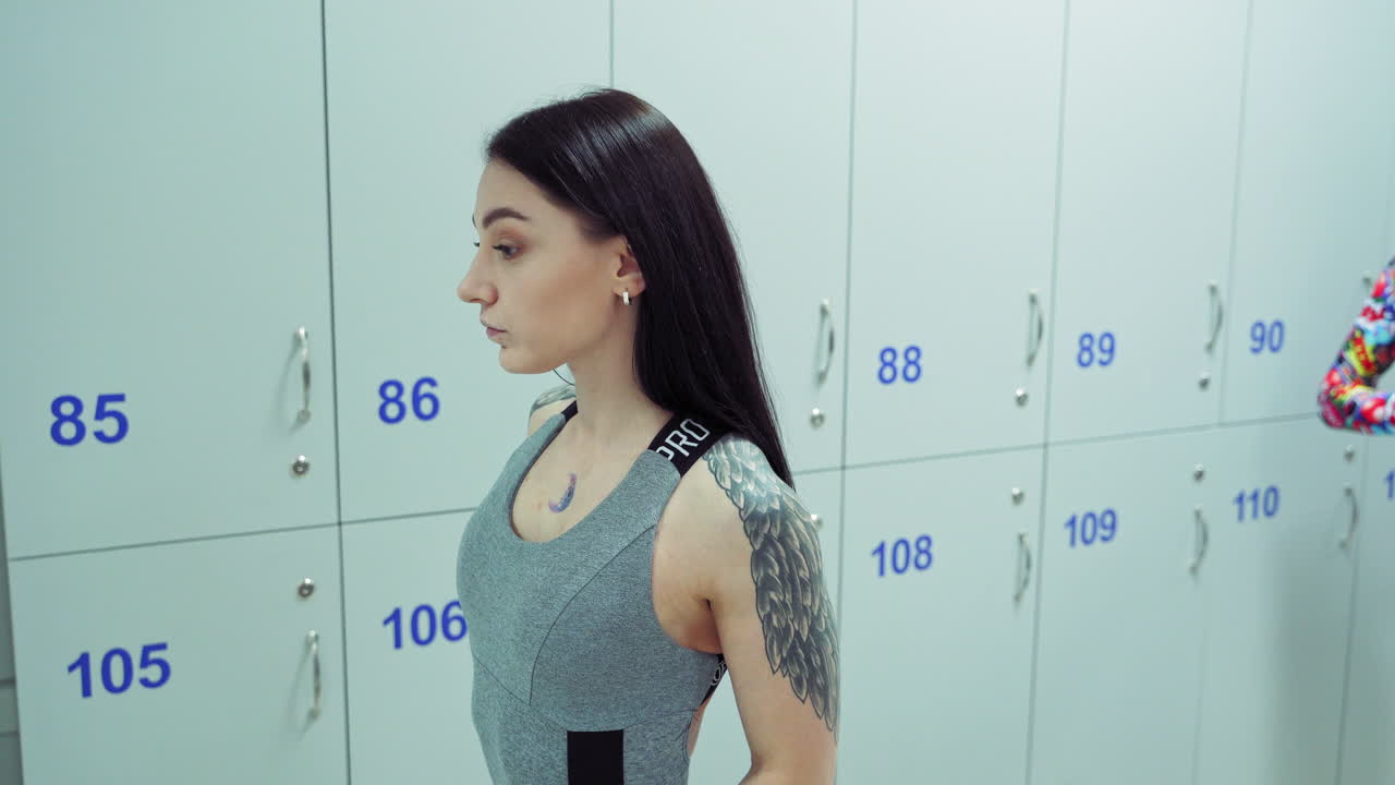 Woman Looking At Reflection In Dressing Room. Woman looking on reflection in the mirror after exercise in gym