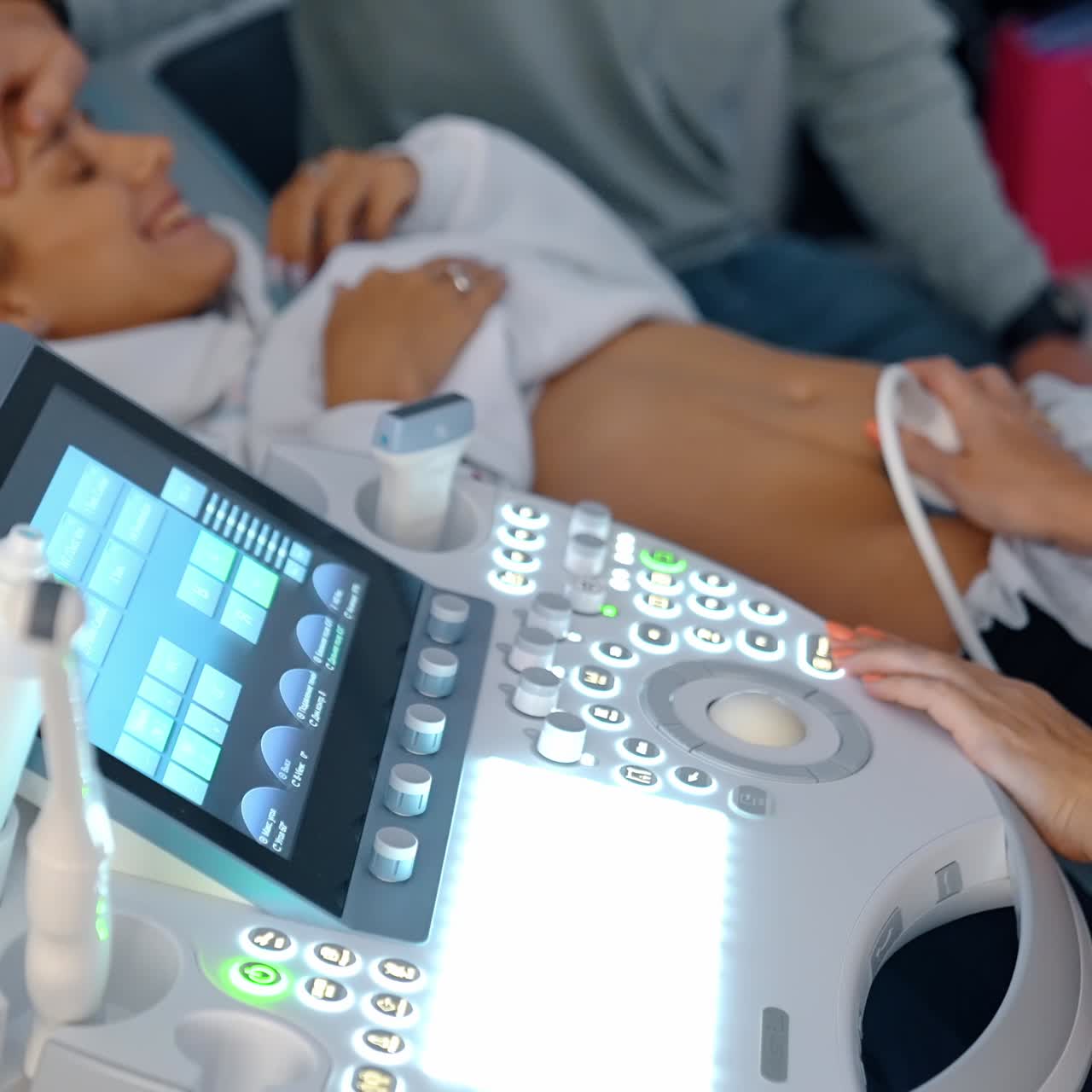 Medic performs ultrasound check up for pregnant lady. Happy woman is smiling seeing her baby