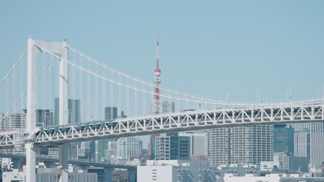 Puente-Del-Arco-Iris-Sobre-La-Bahía-De-Tokio-Con-La-Torre-De-Tokio-Y-El-Horizonte-Contra-El-Cielo-Azul-A-La-Luz-Del-Día-En-Tokio,-Japón