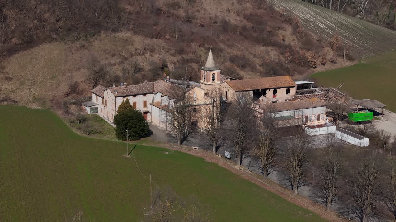 Sant Ilario Vescovo parish church and rural buildings in Chiavenna Rocchetta near Lugagnano Val d'Arda, Piacenza Province, Emilia-Romagna, Italy surrounded by farmland hills