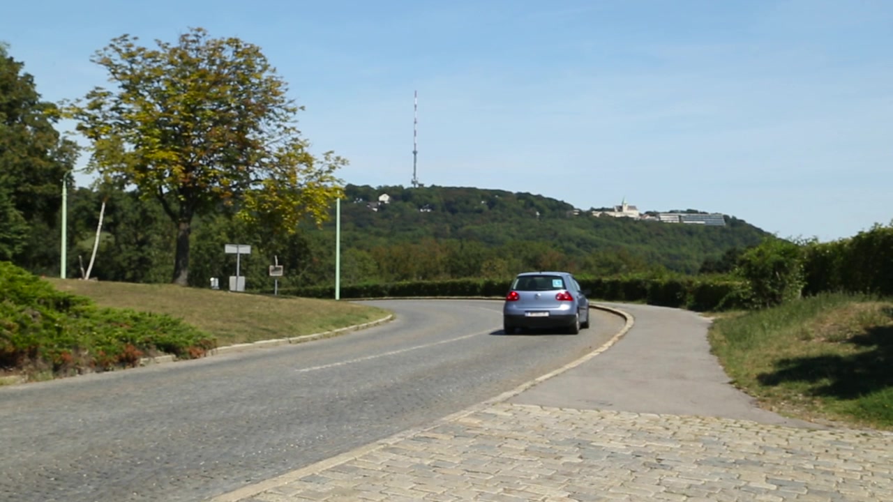 Auto che guida su strada tortuosa con collina sullo sfondo