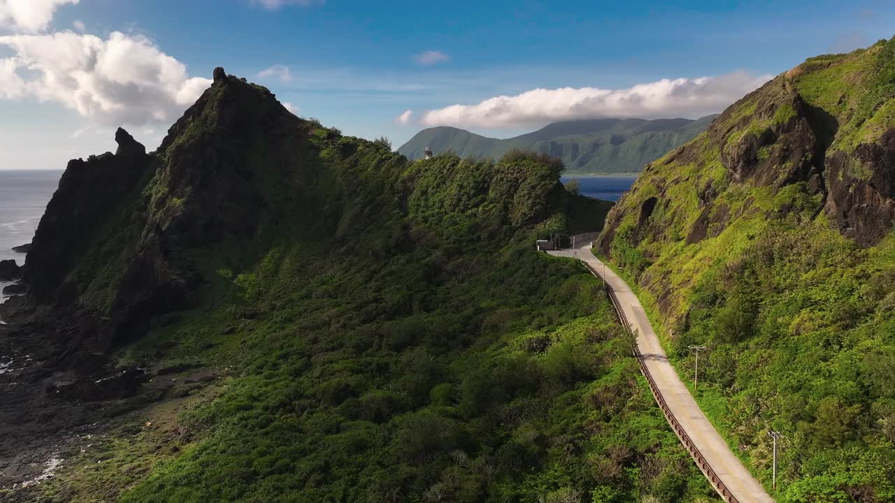 해가 지는 시간에 산과 푸른 바다 사이의 경로와 함께 녹색 오키디 섬을 향한 공중 비행