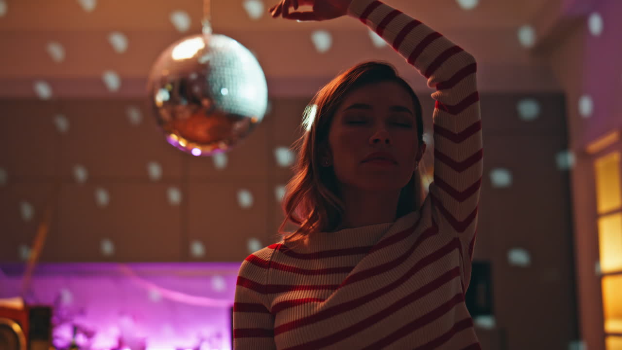 Girl moving body sensually in glowing lights apartment close up. Woman dancing