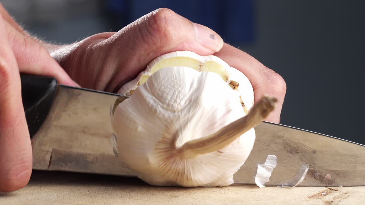 Person cutting a bunch of garlic in half. Close-up