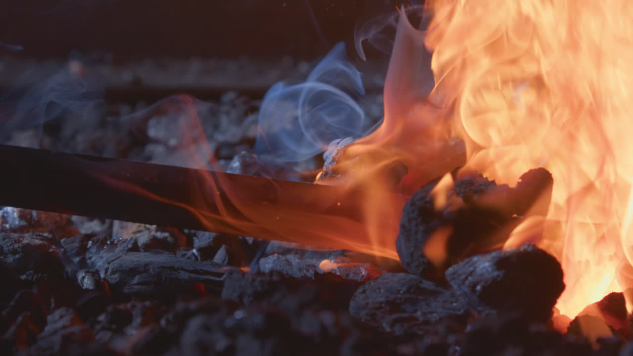 Iron piece being heated in hot fiery furnace of blacksmith workshop, close-up