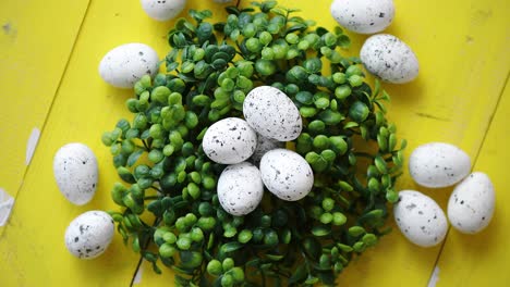 Green-decorative-Easter-quail-eggs-wreath-on-yellow-wooden-table