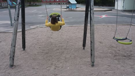 footage of a woman in a yellow sweater using a swing on a school yard-1